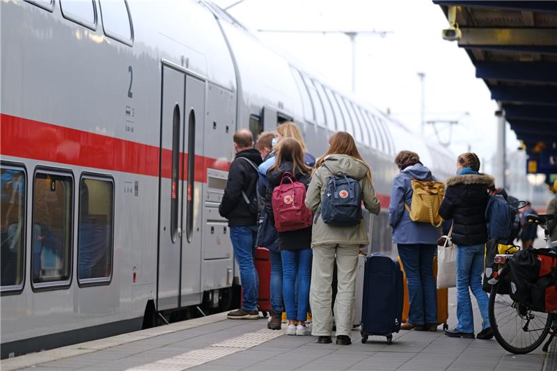 Menschen stehen am Samstagmorgen auf einem Bahnsteig am Bahnhof Norddeich Mole vor einem eingefahrenen Zug. Die Herbstferien in Niedersachsen gehen zu Ende. Foto: Markus Hibbeler/dpa