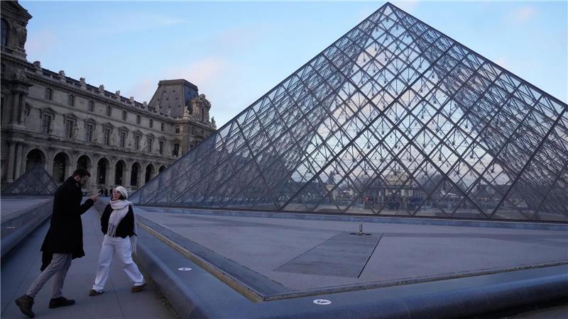 Menschen stehen an der Pyramide des Louvre-Museums am Montagmorgen.