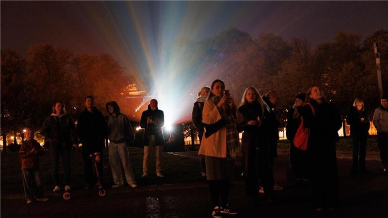Menschen stehen vor einem Beamer, während der Berliner Dom bei der Generalprobe für das 21. Festival of Lights Berlin unter dem Motto „Let’s Shine Together“ angestrahlt wird.
