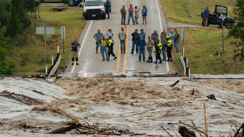 Menschen stehen zusammen und beobachten, wie der Perdenales River die Ranch Road 1623 in  in Texas überflutet.