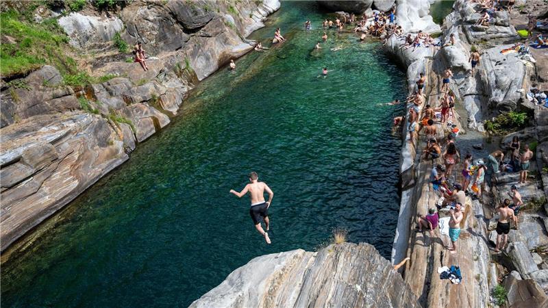 Menschen suchen Abkühlung im Wasser des Flusses Verzasca in der Schweiz.