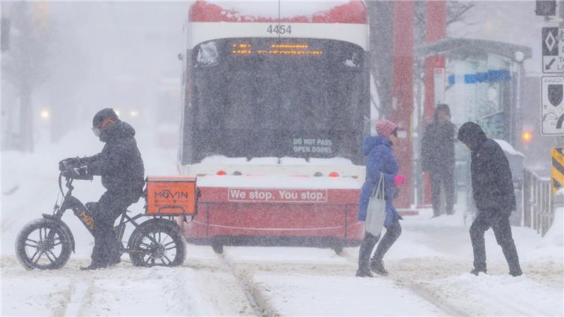 Menschen überqueren eine Straße an einem verschneiten Tag in Toronto, Kanada.
