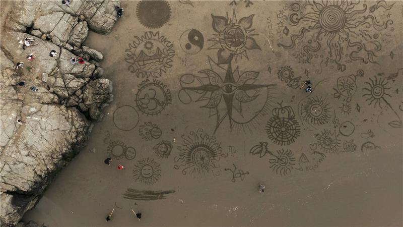 Menschen versammeln sich am Ocean Beach in San Francisco, um bei einer von Künstler Andres Amador organisierten Veranstaltung Kunstwerke im Sand zu gestalten.