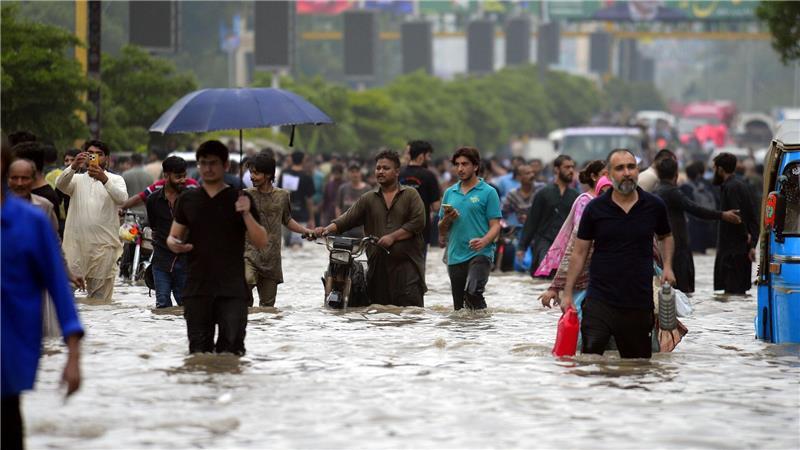 Bilder des Tages Menschen waten durch eine überflutete Straße nach starkem Monsunregen in Pakistan.