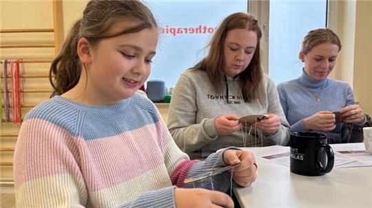 Merve Dalar aus Harsefeld hat schon mehrere Armbänder geknüpft. Im Hintergrund knüpfen Ayleen Dittmer aus Dollern und Ann-Kathrin Wöhlk aus Grünendeich.