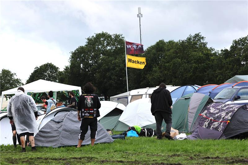 Campen bei Dauerregen: Das macht ein gutes Zelt aus Metal-Fans stehen auf einem der Campingplätze auf dem vom Regen aufgeweichten und schlammigen Gelände des Wacken-Open-Air-Festivals. Foto: Christian Charisius/dpa