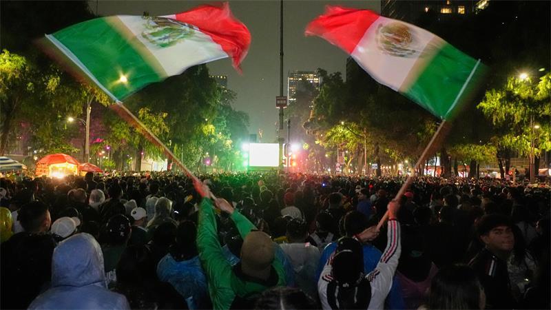 Mexikanische Fans schwenken Fahnen, während sie in der Nähe des Denkmals „Angel of Independence“ das WM-Spiel verfolgen.