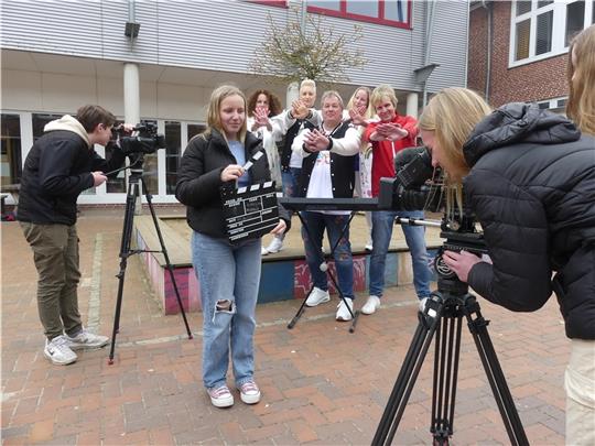 Mia Krönke (rechts) von der Film-AG der EMS gehörte beim Video-Dreh mit den Profimusikern zum Kamerateam. Die Musiker im Hintergrund zeigen beim Singen ihre Abwehrgeste gegen Mobbing. Foto: Knappe