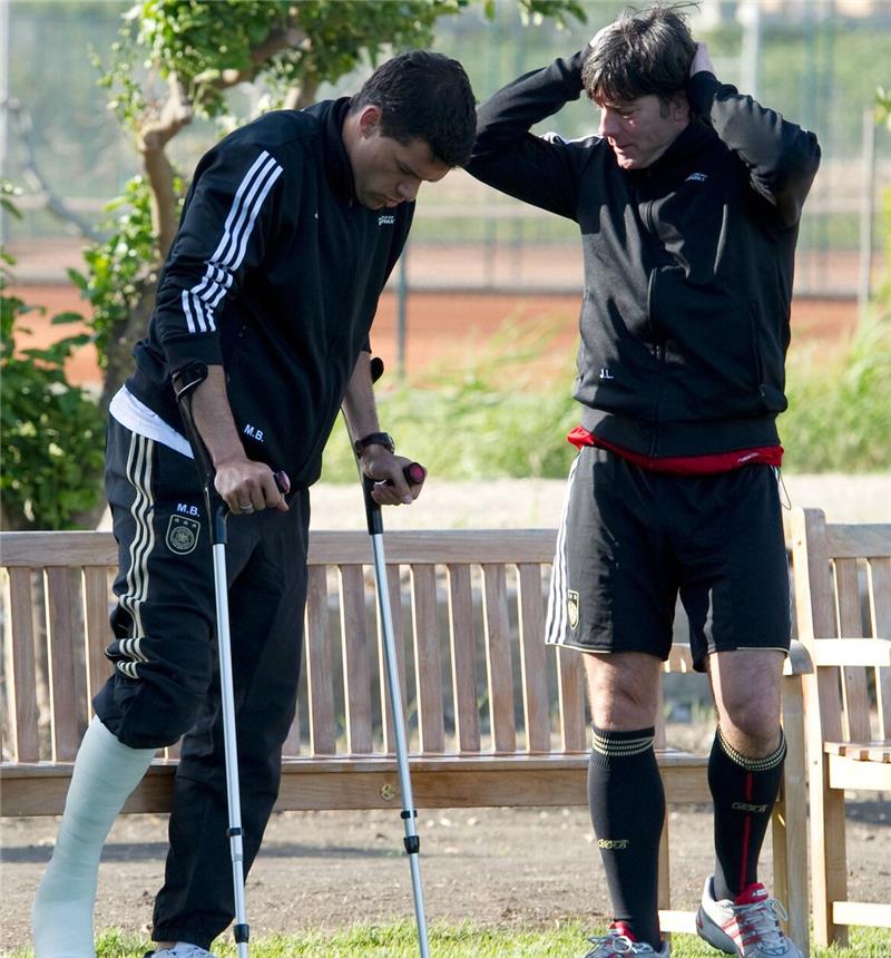 Kimmich neuer DFB-Kapitän? Das ist die turbulente Geschichte der Binde Michael Ballack schaut am 18.05.2010, auf Krücken gestützt, neben Bundestrainer Joachim Löw (r) beim Mannschaftstraining auf der Anlage des Hotel Verdura in Sciacca zu. Auf der italienischen Insel Sizilien bereitet sich die deutsche Nationalmannschaft auf die Fußball-WM 2010 in Südafrika vor.