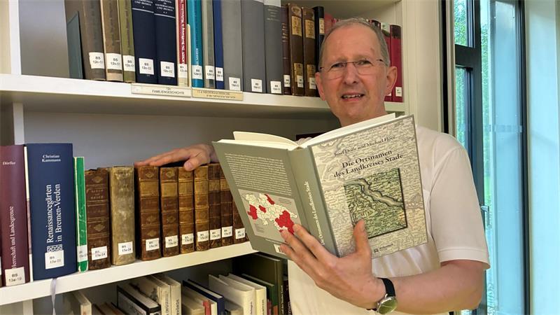 Michael Flöer von der Niedersächsischen Akademie der Wissenschaften zu Göttingen hält das Ortsnamen-Buch in Händen.