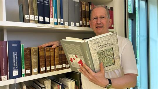 Michael Flöer von der Niedersächsischen Akademie der Wissenschaften zu Göttingen hält das Ortsnamen-Buch in Händen.