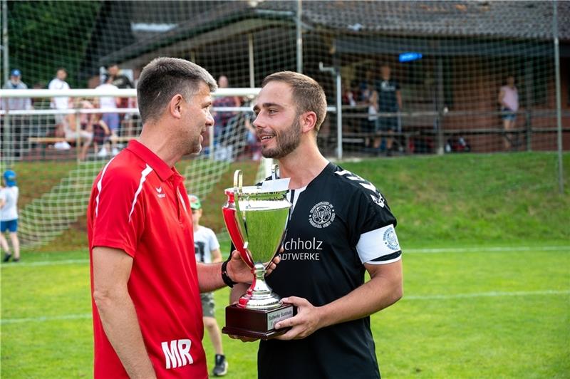 Michael Rump, Trainer des TSV Eintracht Immenbeck, überreicht dem Kapitän des Buchholzer FC den Pokal des Stadtwerke-Cups. Foto: Schmietow