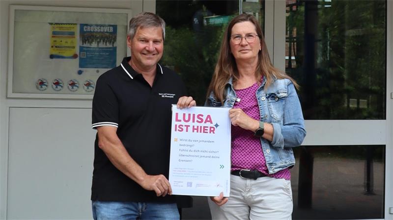 Michael Wege und Jessica Jennrich mit dem Plakat: 'Luisa ist hier' ist ab sofort auch in den Samtgemeinde-Sportstätten ein Schlüsselsatz.
