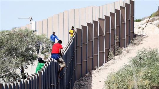 Migranten klettern über einen Zaun auf der Insel Lampedusa.