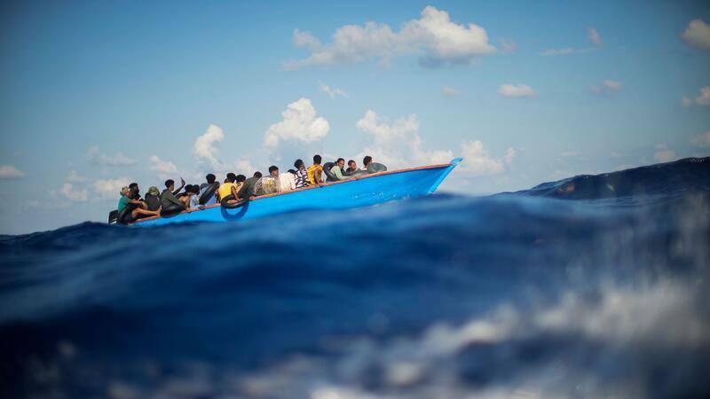 Mehr als 600 Neuankömmlinge auf Lampedusa - Kind vermisst Migranten sitzen in einem Holzboot im Mittelmeer nahe der Insel Lampedusa: Die kleine Insel gehört seit Jahren zu den Brennpunkten illegaler Migration (Archivfoto).