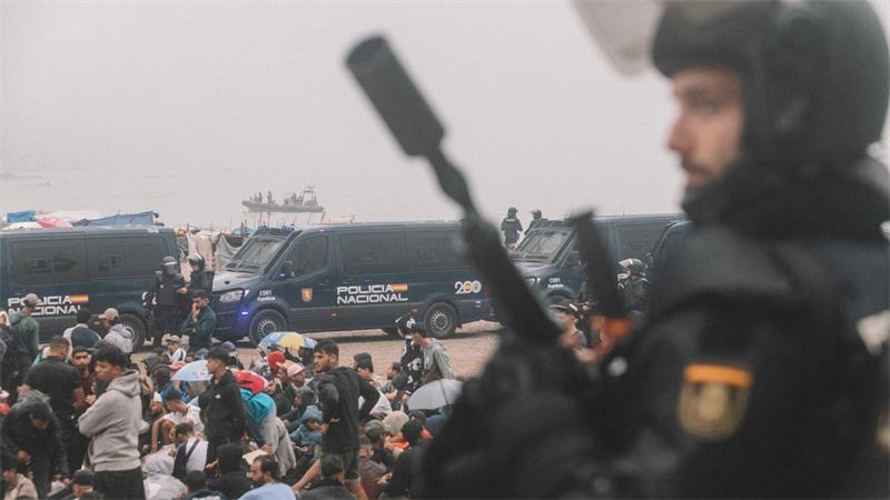 Migranten wurden in Ceuta von starken spanischen Polizeikräften von einem Hüttenlager am Strand fortgebracht. 