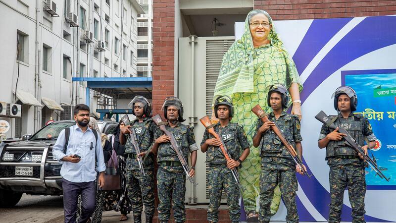 Militärangehörige stehen vor einem großen Porträt von Premierministerin Sheikh Hasina. Sie gilt als autokratisch regierende Premierministerin.