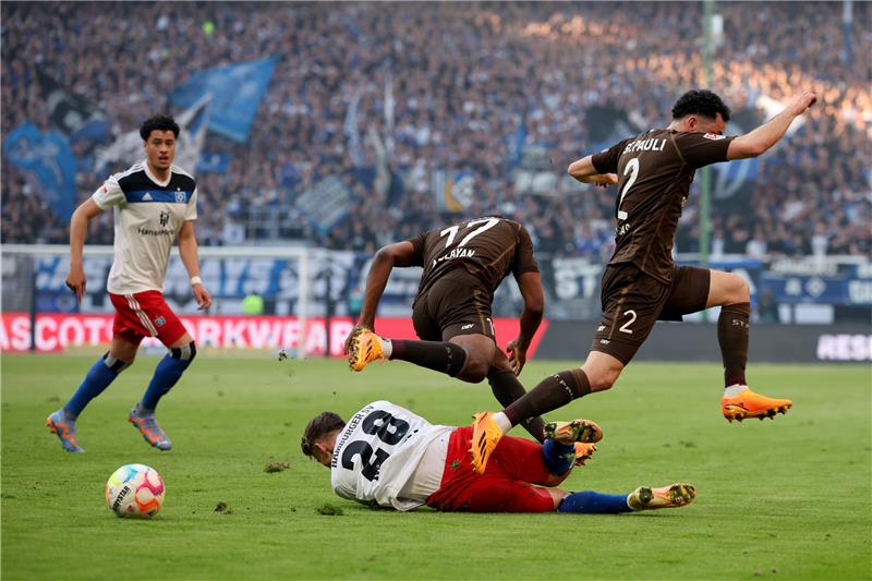 HSV feiert Sieg in aufregendem Stadtderby Miro Muheim vom Hamburger SV (unten) liegt am Boden während die beiden St. Pauli Spieler Oladapo Afolayan (M) und Manolis Saliakas über ihn springen. Foto: Christian Charisius/dpa