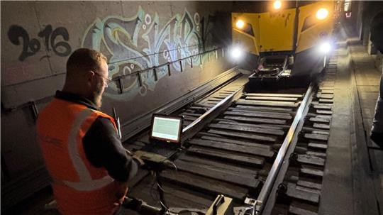 Mit Blick auf ein Display begleitet ein Arbeiter den Spezialzug beim Fräsen der Schiene. Die Maschine trägt dünne Metallschichten ab und saugt die entstehenden Frässpäne auf.