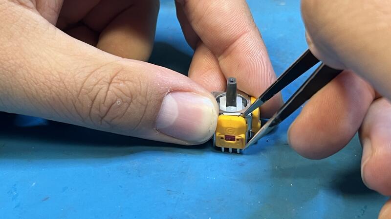 Mit Feinwerkzeug nimmt der Reparaturtechniker die Bestandteile der Elektrogeräte unter die Lupe.