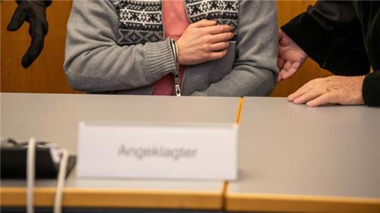 Mit Handschellen gefesselt sitzt ein Mann im Landgericht auf der Anklagebank.