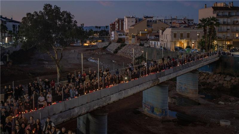 Mit Kerzen in Händen bilden Teilnehmer einer Gedenkveranstaltung eine Menschenkette in Paiporta in der Region Valencia, um an die Opfer der Flutkatastrophe vom Oktober 2024 zu erinnern. 