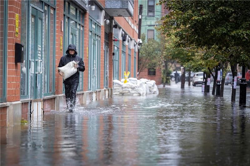 New York versinkt im Regen Mit Sandsäcken versucht ein Mann zu verhindern, dass Wasser in ein Gebäude eindringt.