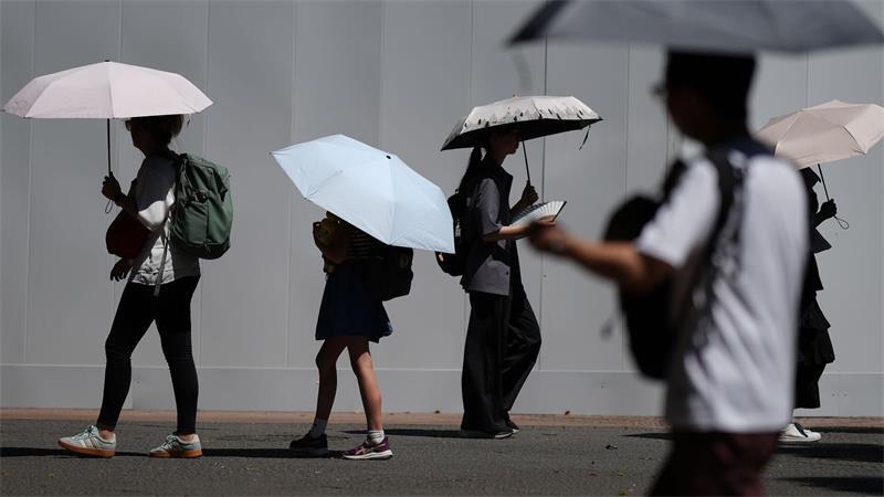 Mit Schirmen schützen sich Menschen vor der sengenden Sonne in Tokio.