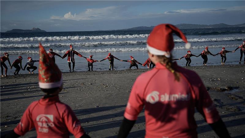 Mit Weihnachtsmannmützen verkleidete Menschen surfen während der „Papanoelada Surfera“ (Surfer-Nikolaus-Aktion) am Strand von Patos. 