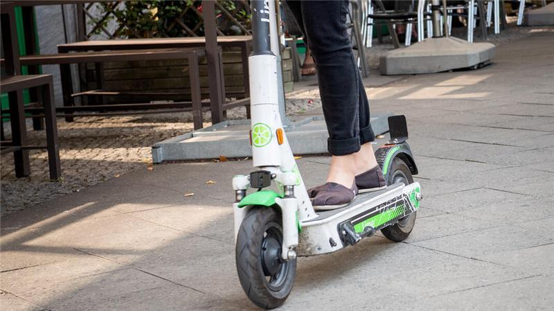 Ein E-Scooter fährt auf einem Gehweg.