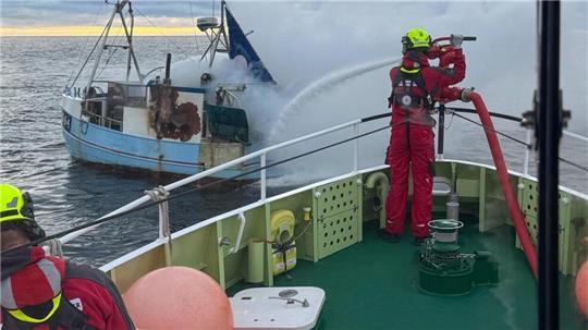 Mit dem leistungsstarken Feuerlöschmonitor des Seenotrettungskreuzers FRITZ KNACK löscht die Besatzung den Brand auf dem havarierten Fischkutter.
