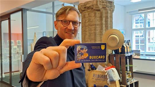 Stadtmarketing-Leiter Torsten Lange hält die BUXCard in Richtung Kamera