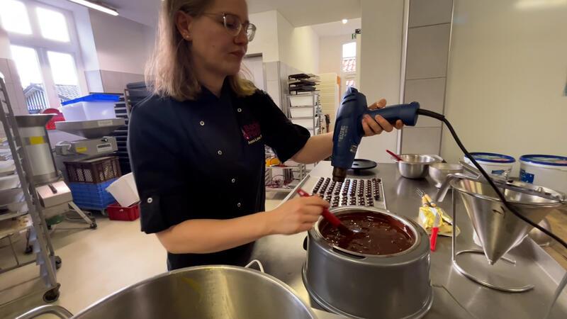 Diese Konditormeisterin macht feinste Pralinen im Alten Land Mit einem Heißluftföhn wird die dunkle Kuvertüre auf die richtige Temperatur gebracht.