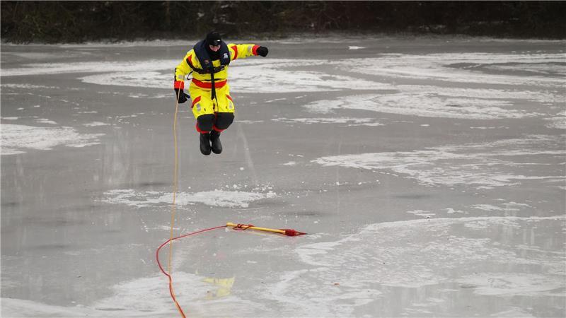 Mit einem Sprung versucht Feuerwehrmann Jannis Greve ins Eis des Öjendorfer Sees einzubrechen, um mit seinen Kameraden eine Rettung zu üben.