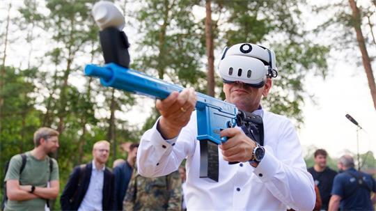 Mit einem Übungsgewehr und einer Virtual-Reality-Brille übt Regierungschef Lies virtuell den Abschuss feindlicher Drohnen.