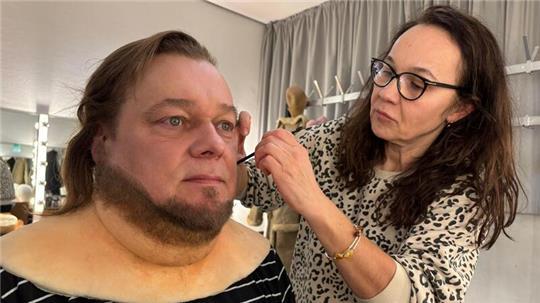 Mit einem feinen Pinsel trägt die Maskenbildnerin den Spezialkleber für den Bart auf.