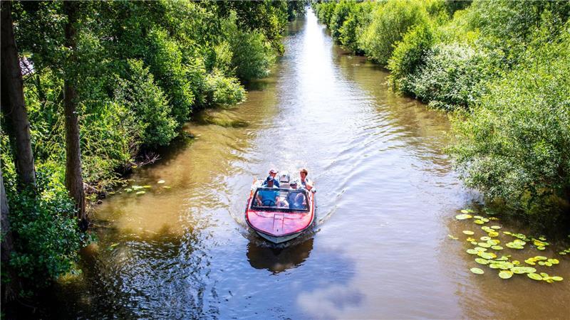Mit einem kleinen Motorboot sind Urlauber auf dem Langen Graben zwischen Ziegelsee und Schweriner See unterwegs.
