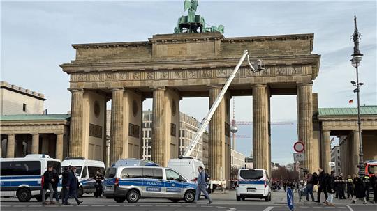 Mit einer Arbeitsbühne fahren Höhenretter der Polizei auf das Brandenburger Tor um ein Transparent zu entfernen. Mehrere Demonstranten sind auf das Brandenburger Tor in Berlin geklettert und haben ein israelfeindliches und propalästinensisches Transparent aufgehängt.