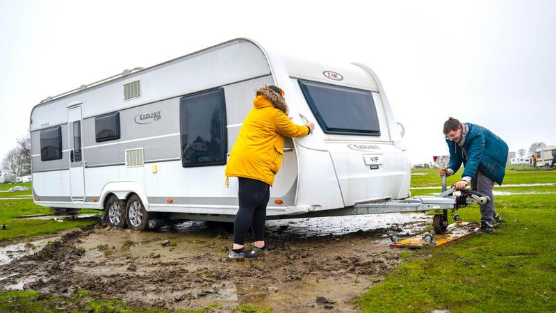 Mit gegenseitiger Unterstützung schieben die Urlauber ihre Wohnwagen auf die Parzellen.