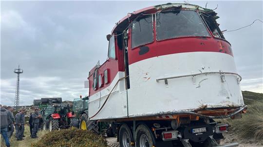 Mit mehreren Traktoren wurde der vor Sylt angespülte Aufbau eines ehemaligen Lotsenbootes hinter die Düne in Hörnum (Sylt) gezogen. 