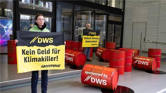 Mit roten Ölfässern protestieren Aktivisten von Greenpeace vor der Zentrale von DWS Investment in Frankfurt gegen die Investitionspolitik des Fonds.