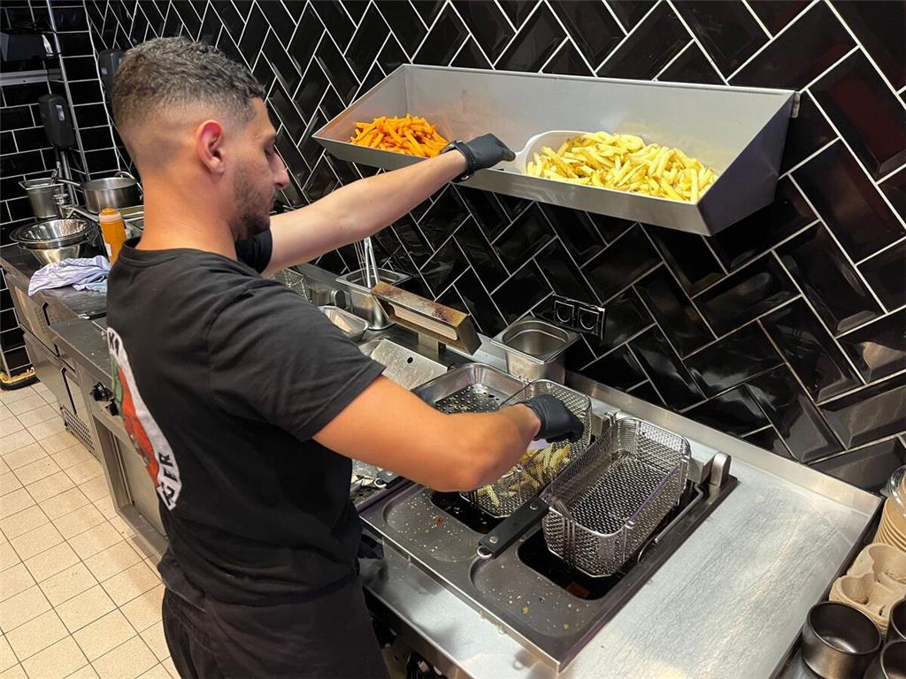 Mitarbeiter Mohamed fängt mit dem Frittieren der Pommes an.