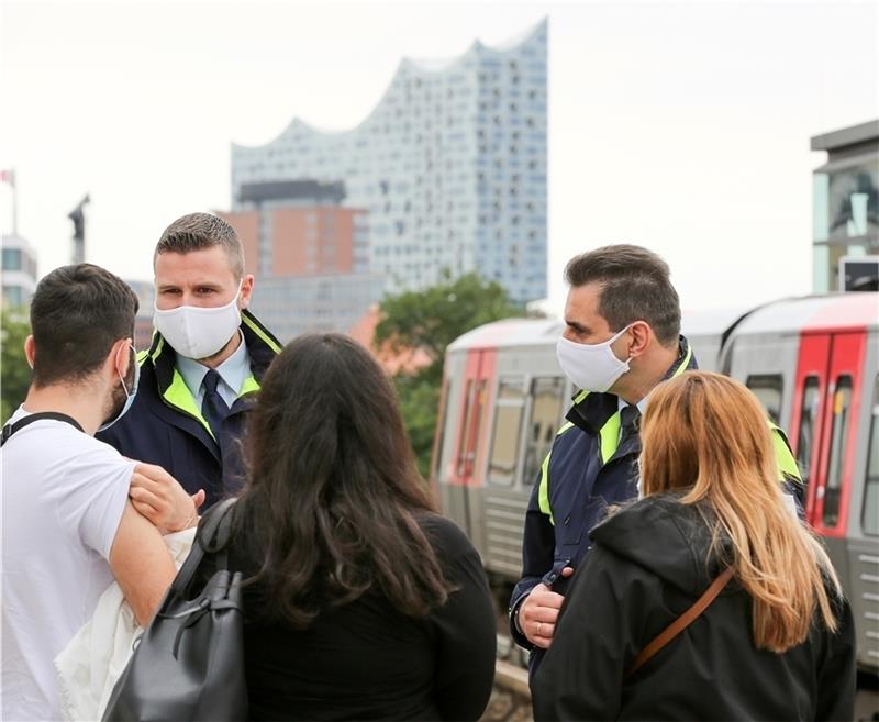 Mitarbeiter der Hochbahn-Wache stellen bei einer Fahrgastgruppe am U-Bahnhof Landungsbrücken Verstöße gegen die Maskenpflicht fest und stellen Strafen aus. Foto: Marks/dpa