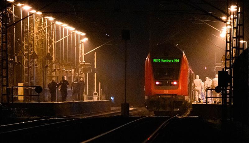 Mitarbeiter der Spurensicherung sind auf einem Bahnsteig an einem Regionalzug im Einsatz, gegenüber stehen Polizisten. Bei einer Messerattacke in einem Regionalzug von Kiel nach Hamburg sind zwei Menschen getötet und mehrere verletzt worden. Fotos: Jonas Walzberg/dpa