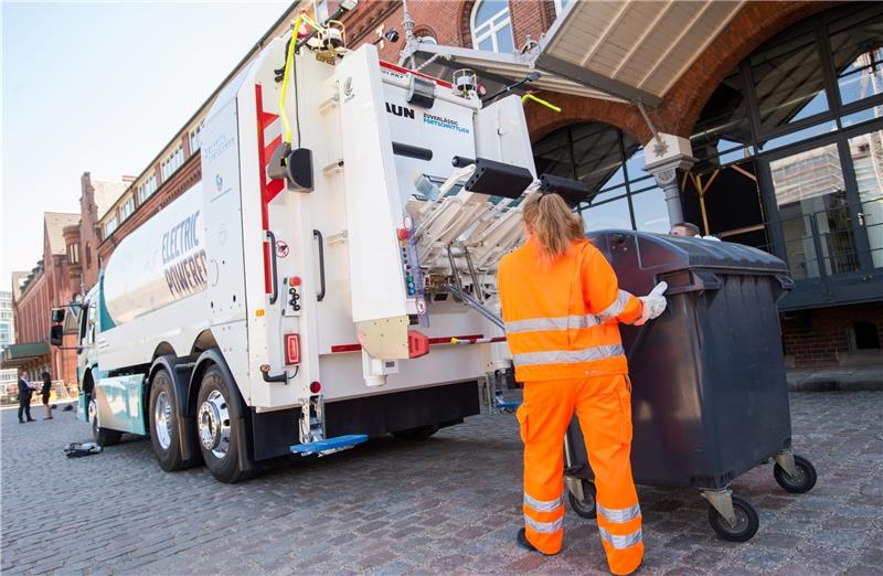 Mitarbeiter der Stadtreinigung leeren eine Mülltonne in den elektrobetriebener Müllwagen vom Typ Volvo FE Electric. Foto: dpa