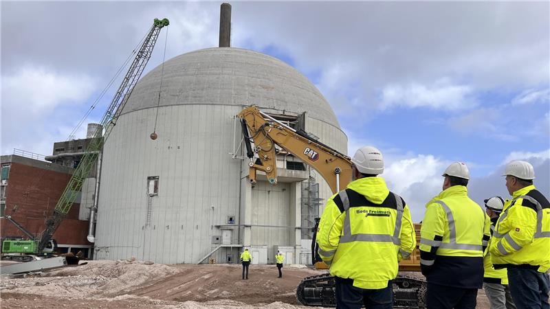 Mitarbeiter der am Rückbau beteiligten Firmen verfolgen das Spektakel am Dienstagmittag. Jetzt geht es der weithin sichtbaren AKW-Betonkuppel an den Kragen.