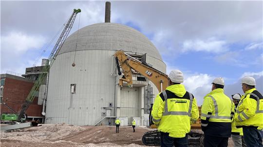 Mitarbeiter der am Rückbau beteiligten Firmen verfolgen das Spektakel am Dienstagmittag. Jetzt geht es der weithin sichtbaren AKW-Betonkuppel an den Kragen.