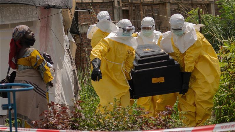 Mitarbeiter des Roten Kreuzes tragen in Schutzanzügen den Sarg einer an Ebola verstorbenen Person aus einem Gesundheitszentrum in Rwampara.