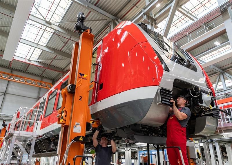 Mitarbeiter im Werk montieren einen Waggon für eine S-Bahn. Foto: Robert Michael/dpa-Zentralbild/dpa