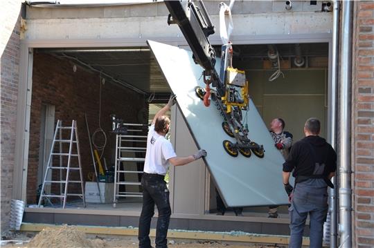 Mitarbeiter von Stader Glas und der Baufirma Menke bauten am Donnerstag einen Großteil der Fenster in das neue Dorfgemeinschaftshaus ein. Fotos: Helfferich